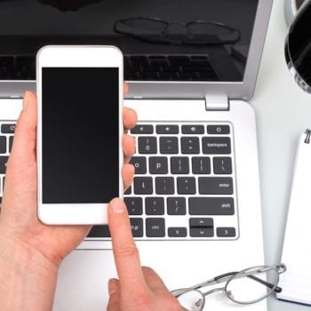 Person using iphone in front of laptop