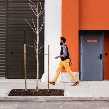 man walking down the street in front of an orange wall