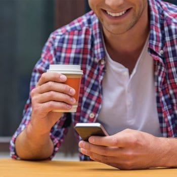 man holding coffee and a cell phone