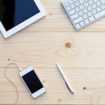 iphone, ipad, pen, and keyboard on a desk