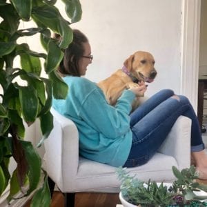 Woman sitting on chair with yellow dog.