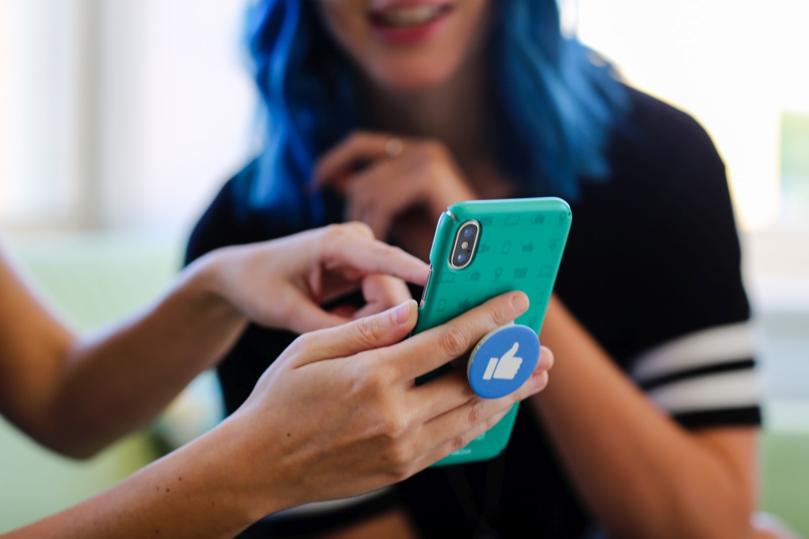 Woman looks as another woman points at iPhone screen