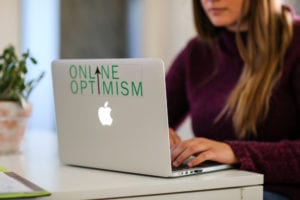 A young woman typing on an Online Optimism laptop.