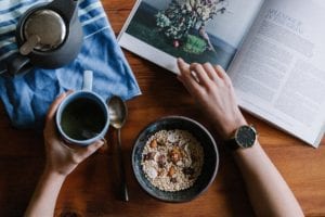 An example of a stock photo from unsplash.com, in which someone holds a cup of coffee while flipping through a book.