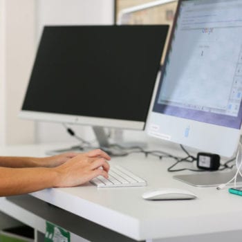 An Online Optimism employee typing on a computer keyboard.