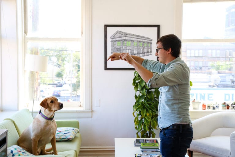 Flynn, Online Optimism's CEO, standing and playing with his dog, Pimm's.