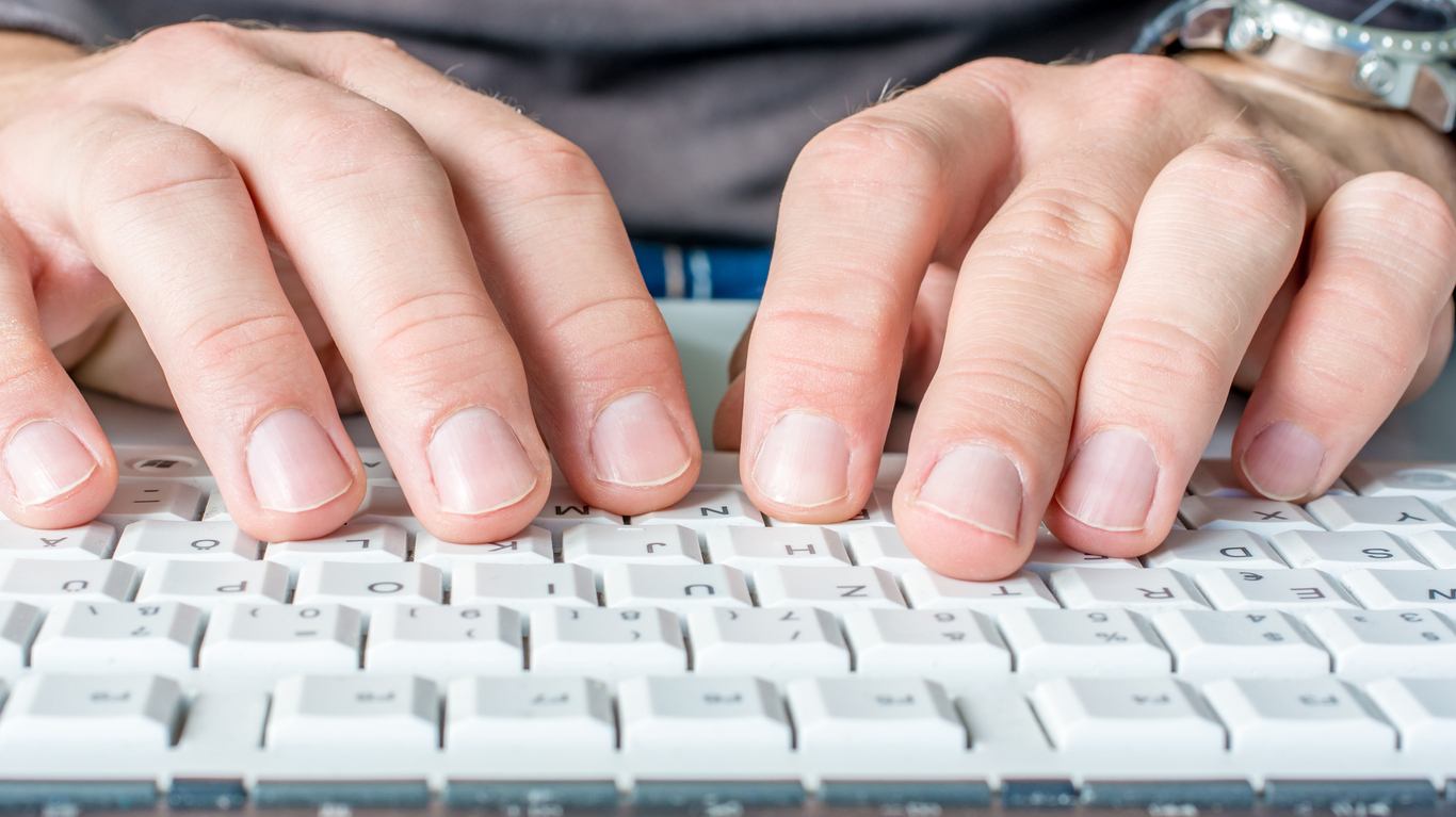 Hands typing on a computer keyboard.