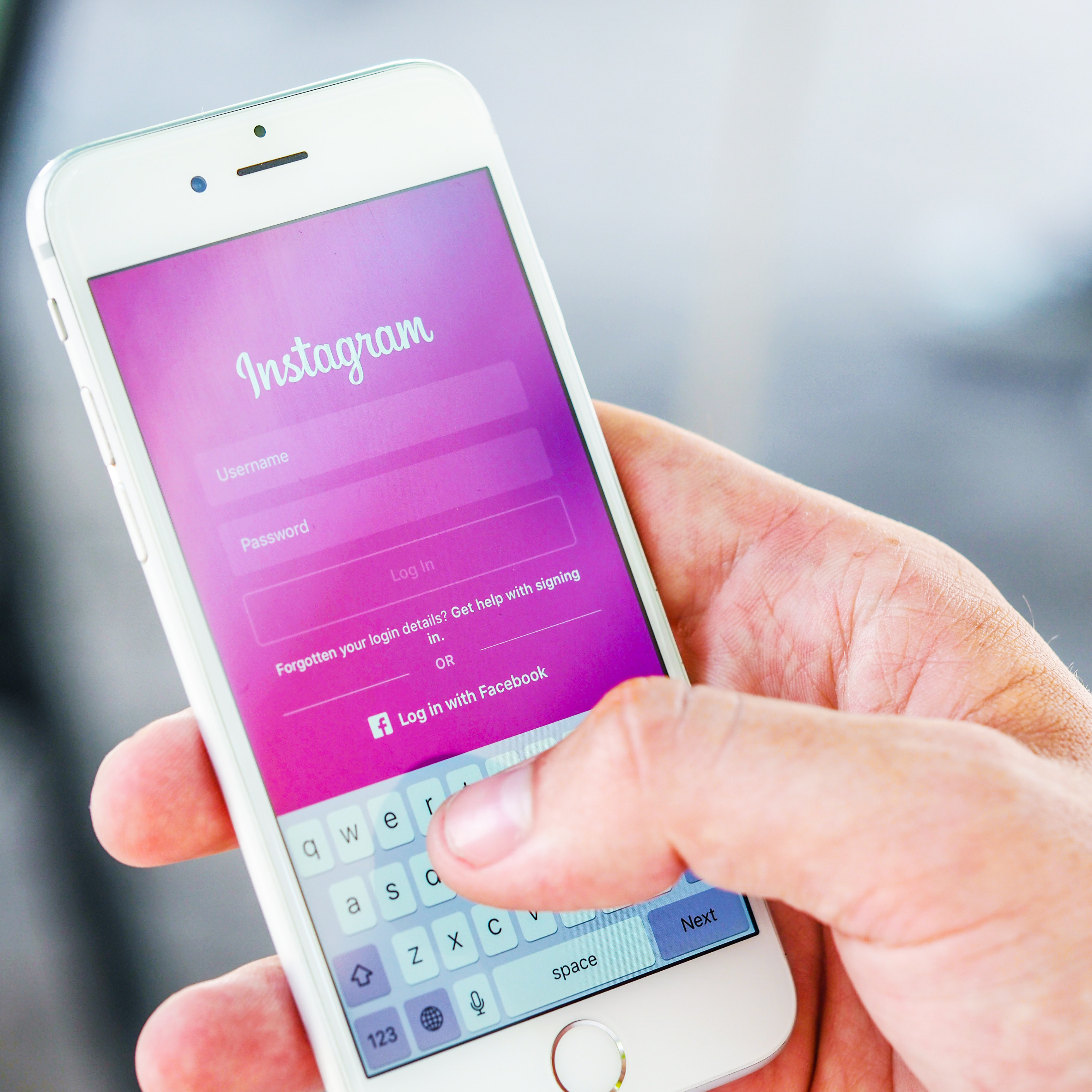 Someone holding an iPhone and logging into Instagram. Learn how to create Instagram Highlights for businesses.