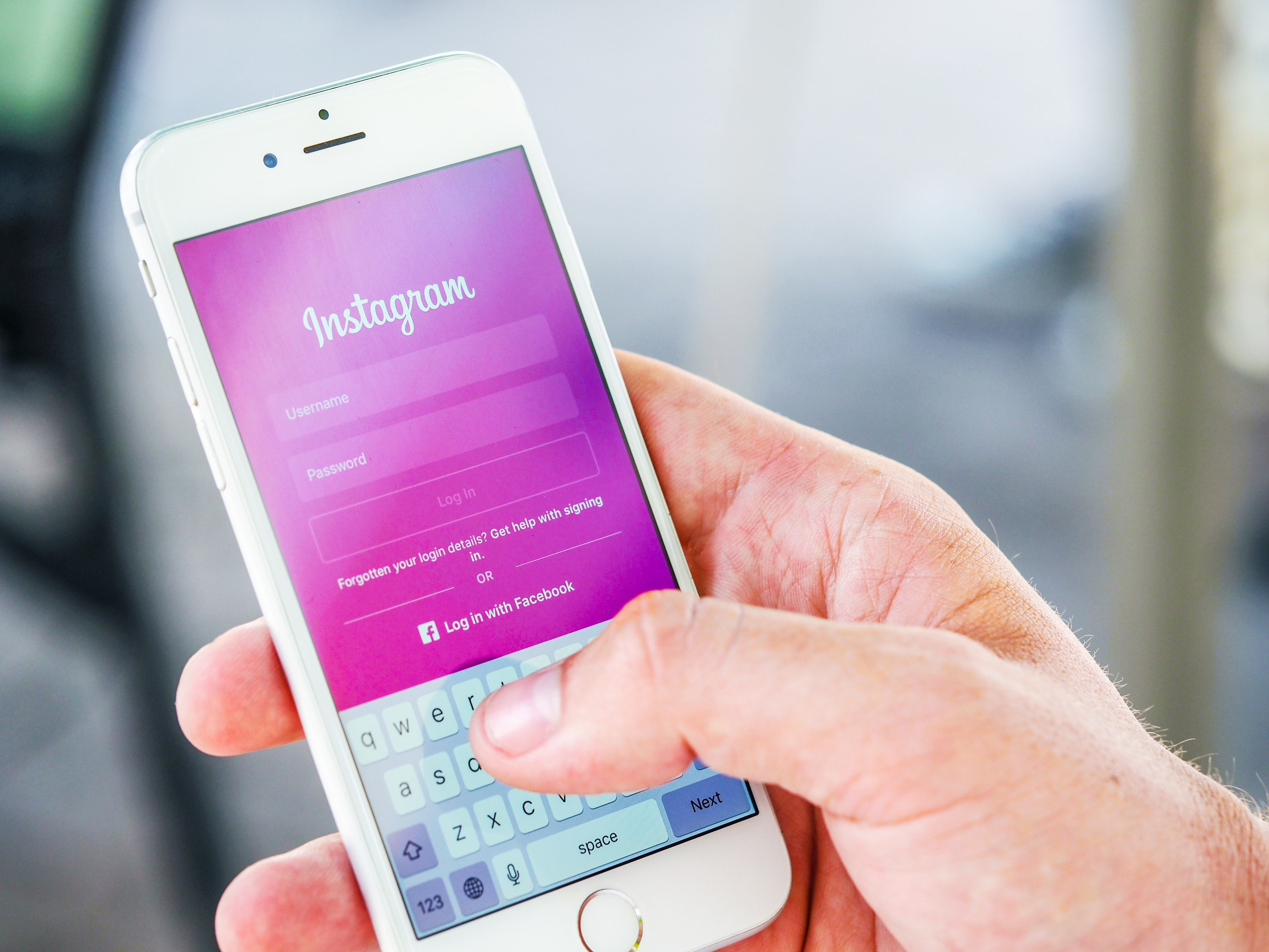Someone holding an iPhone and logging into Instagram. Learn how to create Instagram Highlights for businesses.
