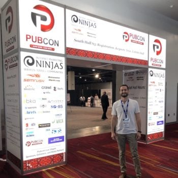 Sam smiling and standing in front of arch entrance to PubCon