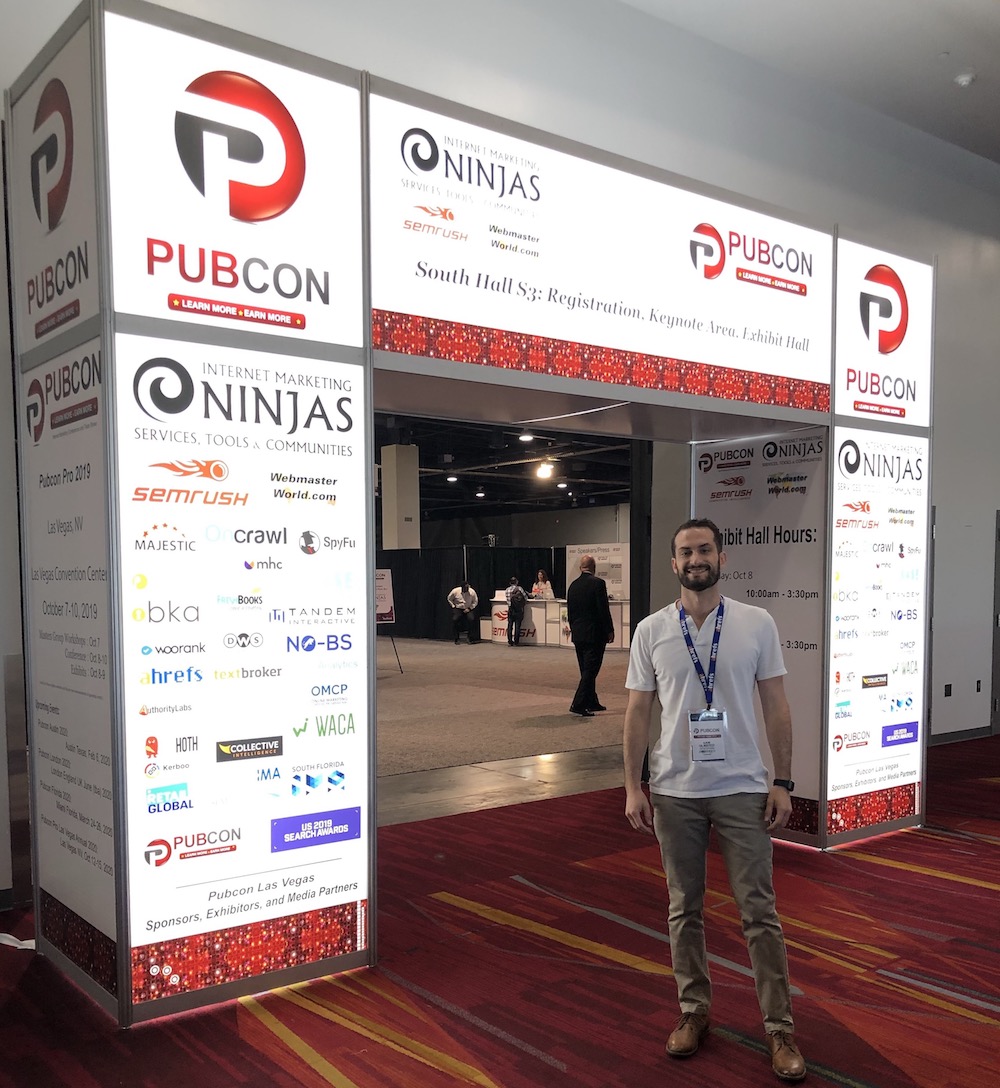 Sam smiling and standing in front of arch entrance to PubCon