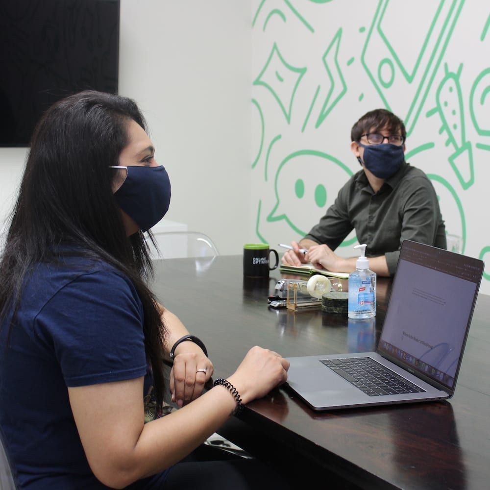Two Optimists wearing masks, working in conference room