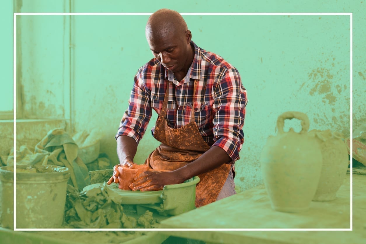 An artist is throwing a bowl on a pottery wheel in a studio.