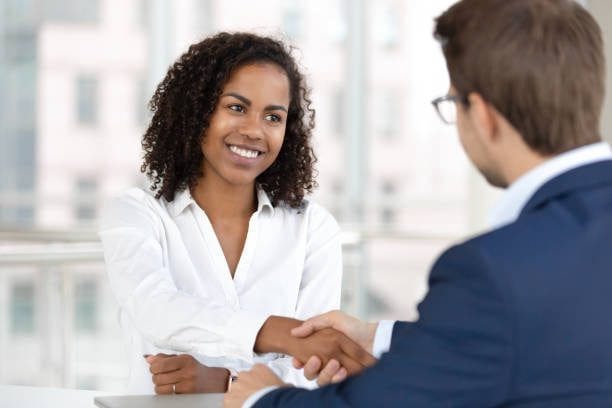 A customer relationship manager shaking hands with a potential client after a meeting. Business development specialist job description 