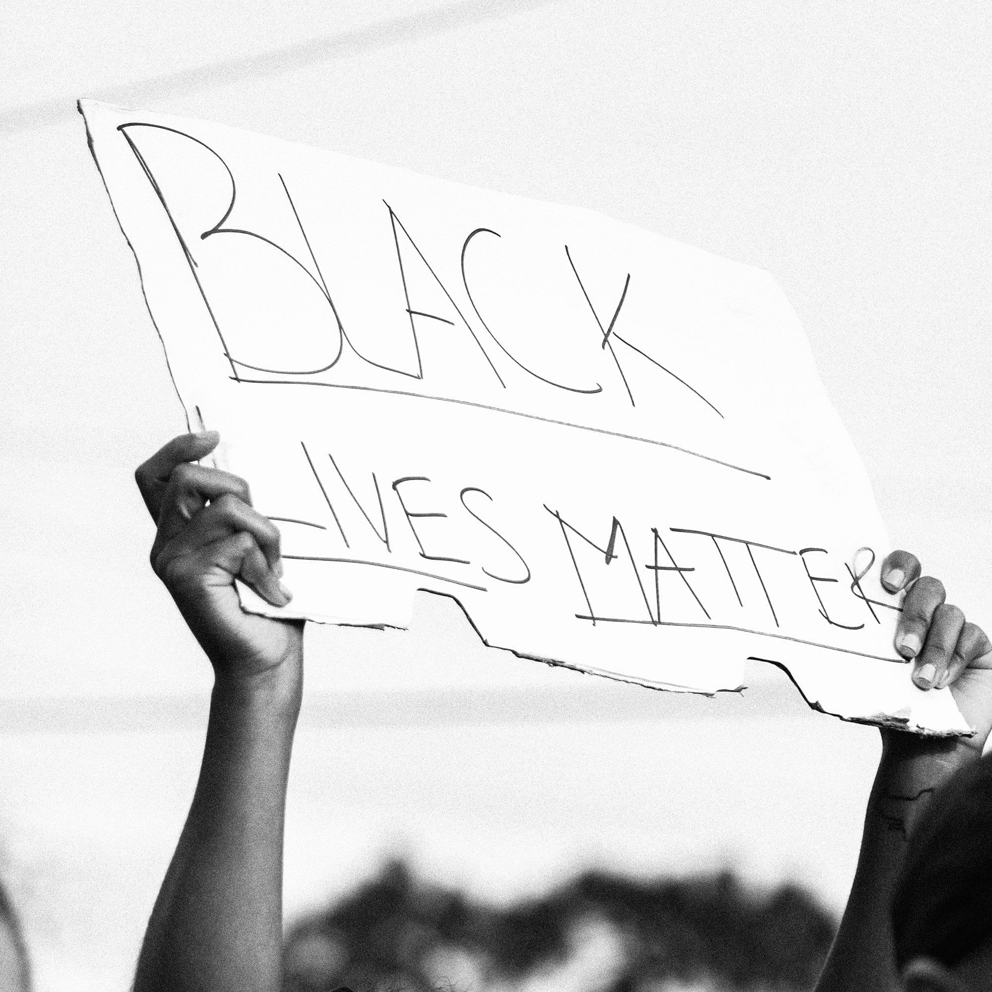 Person holds a sign in the air that reads "Black Lives Matter" at a protest.