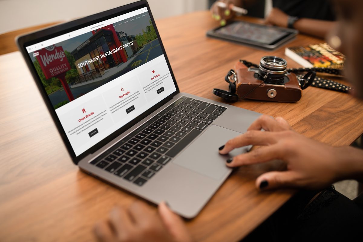 A person sitting at a desk looks at Southeast Restaurant Group's website on their laptop.