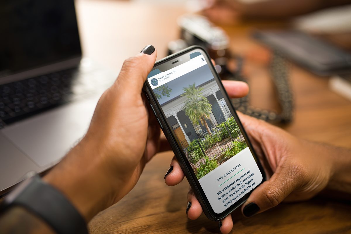 A person with nail polish looks at Witry Collective's site on their phone.