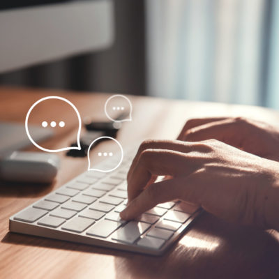 Woman hand typing on keyboard laptop with chat bubbles