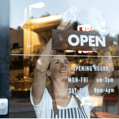 Business-owner hanging an "Open" sign at her store