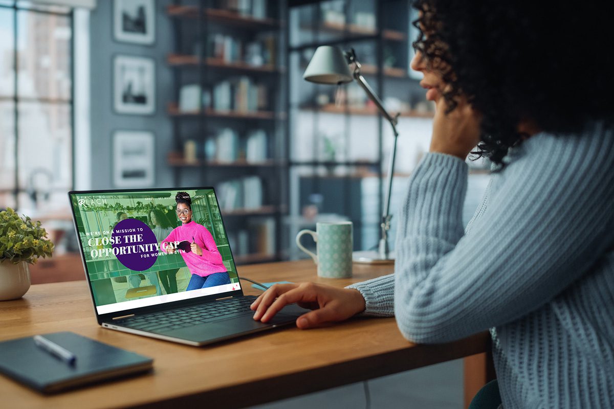 Black female STEM worker uses Space to Reach's website on a laptop