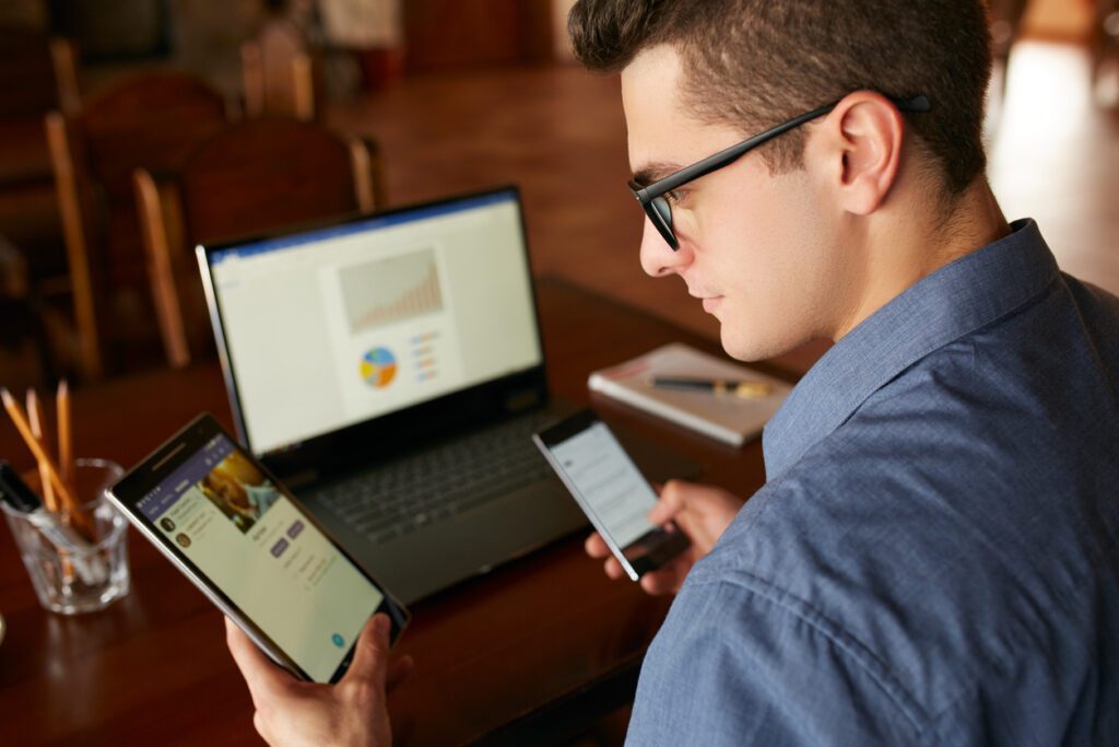 gen z man using ipad, phone, and laptop