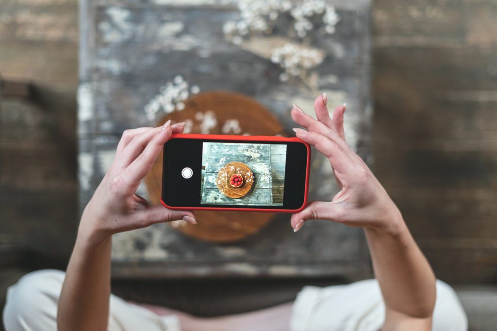 Young adult food stylist woman taking photo on smartphone