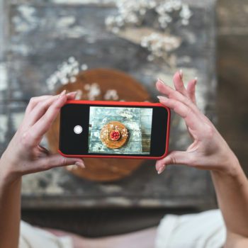 Young adult food stylist woman taking photo on smartphone