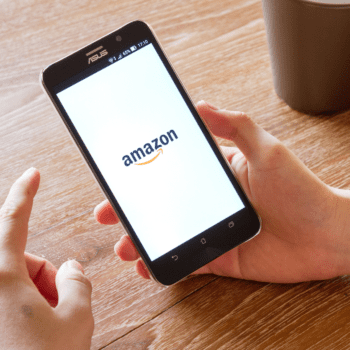 Hands hold a cellphone with the Amazon shopping logo pulled up onscreen