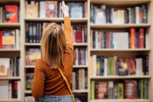 woman reaching on book shelf