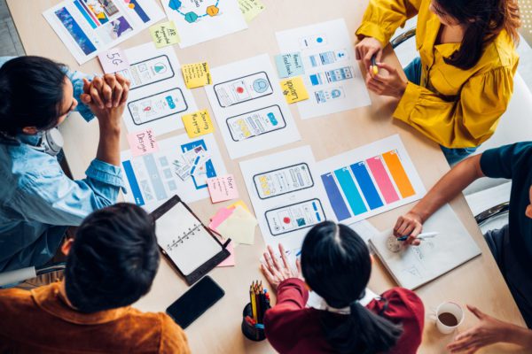 group of people sitting around a table with design mockups