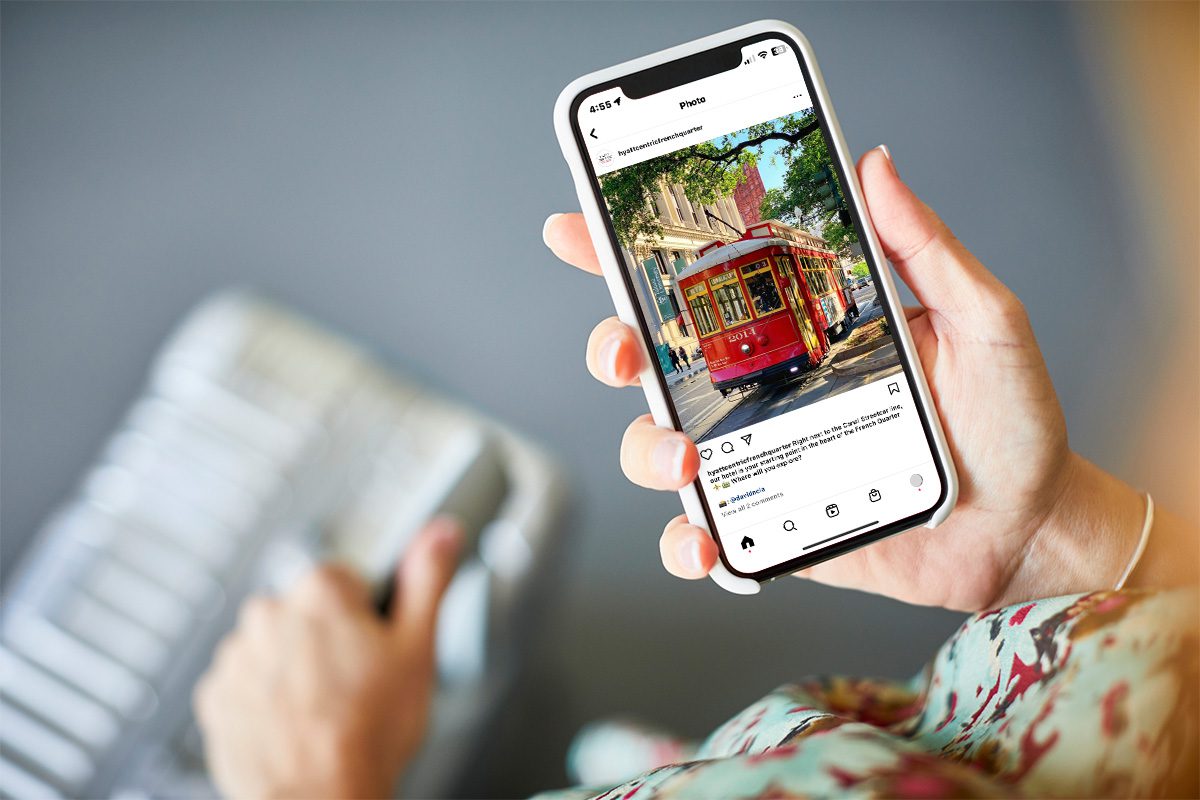 Woman looks at an Instagram post of the Canal Streetcar on Hyatt Centric's account while standing with a suitcase