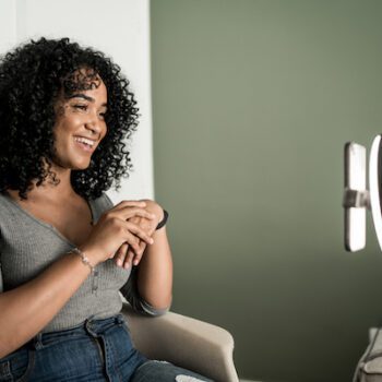 Fixing an Instagram reach drop, symbolized by a smiling woman recording herself talking to her cell phone in a ring light stand