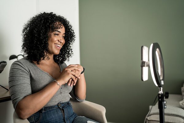 Fixing an Instagram reach drop, symbolized by a smiling woman recording herself talking to her cell phone in a ring light stand