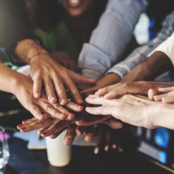 A group of people put their hands together in a circle over a table.